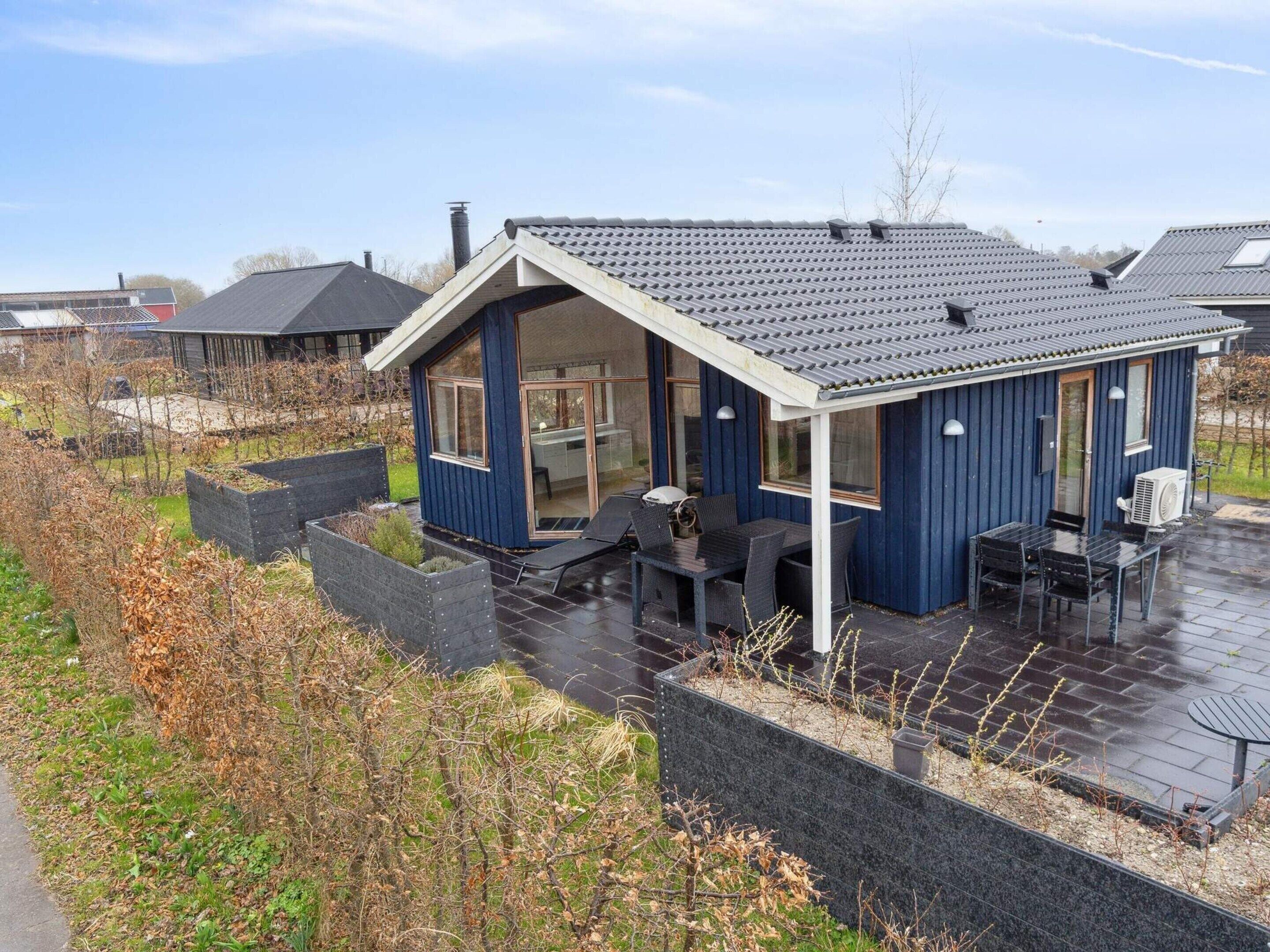 A blue house with a covered patio, a dining area, and a garden with raised beds.