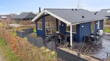 A blue house with a covered patio, a dining area, and a garden with raised beds.