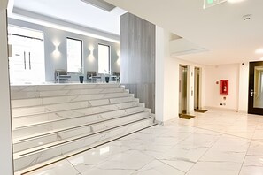 A modern hotel lobby with marble stairs, a reception desk, and a large window. - Depto. moderno con aire acondicionado (Santiago)