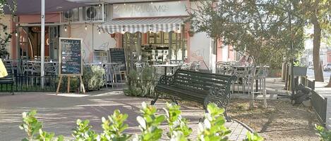 A café with outdoor seating, a bench, and a signboard with menu items.