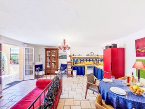 A dining area with a table set for two, a red cabinet, and a kitchen in the background. - Villa Vivaris (VEN111) by Interhome (Vence)