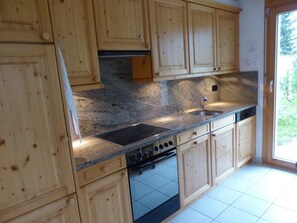 A kitchen with wooden cabinets, a stainless steel sink, a built-in oven, and a dishwasher. - Cresta Sartons Brenn Appartement/Fewo, Badewanne, 1 Schlafraum by Interhome (Valbella)