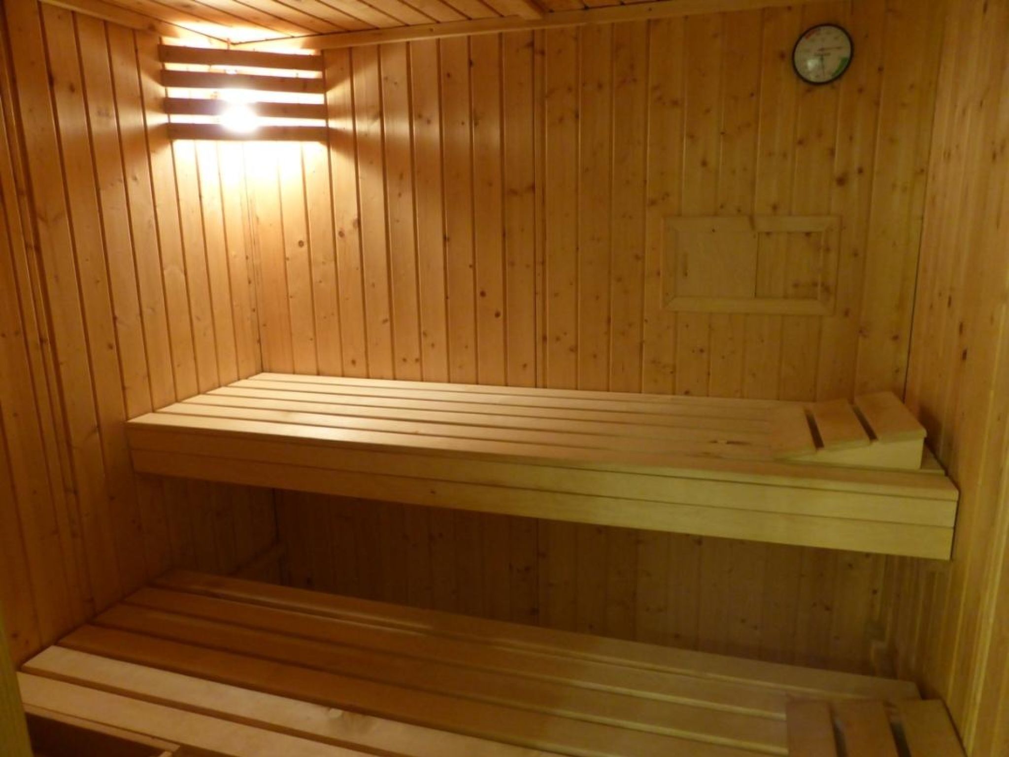 Una sauna con bancos de madera y un reloj en la pared.