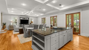 A modern kitchen with a central island, built-in appliances, and a dining area with grey chairs. - STEPS to Camp WaterColor! LSV/Golf Cart & 4 Bikes Included! (Santa Rosa Beach)