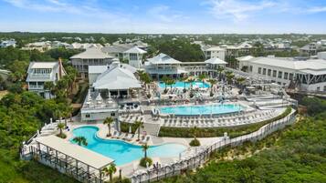 A resort with multiple swimming pools, lounge areas, and a view of the surrounding neighborhood.