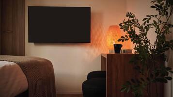 Un dormitorio con una cama, un escritorio con lámpara y un televisor de pantalla plana grande montado en la pared.