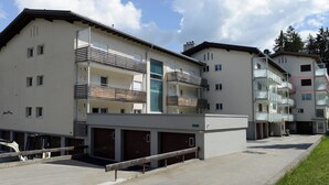 Een meerhoog woongebouw met balkons, een garage en een heldere lucht.