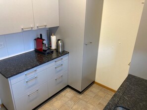 A kitchen with a black countertop, white cabinets, and a stainless steel coffee maker. - Haus Montana 3/6 Appartement/Fewo,   4-Bettwohnung by Interhome (Lenzerheide)