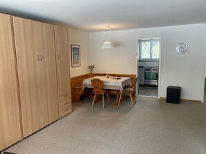 A compact kitchen with a stove and oven, a dining area with a table and chairs, and a large wardrobe. - Haus Montana 3/6 Appartement/Fewo,   4-Bettwohnung by Interhome (Lenzerheide)