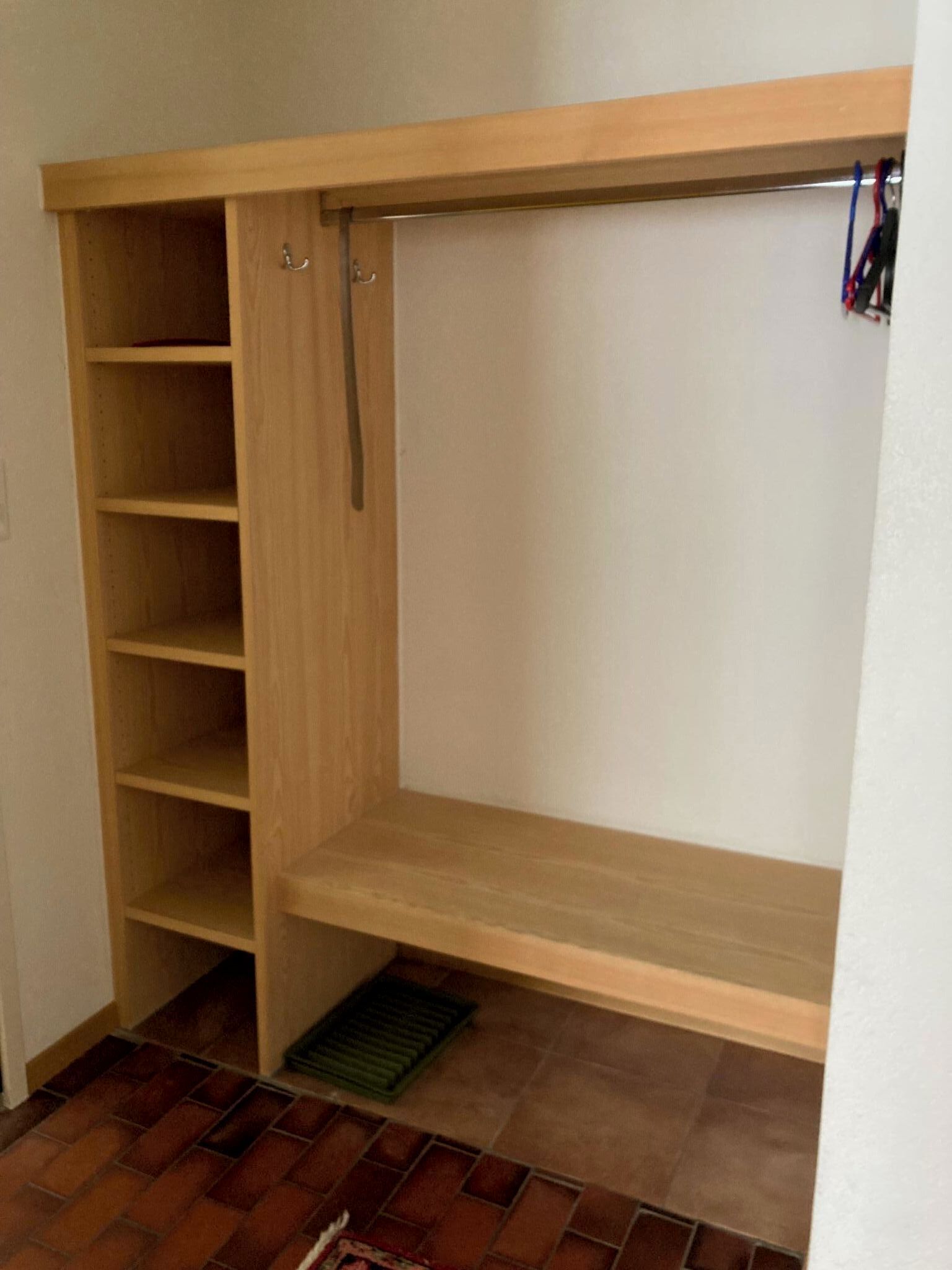A walk-in closet with wooden shelving, a hanging rod, and a vent.