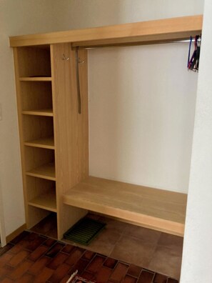 Ein begehbarer Kleiderschrank mit Holzböden, Kleiderstange und Lüftung.