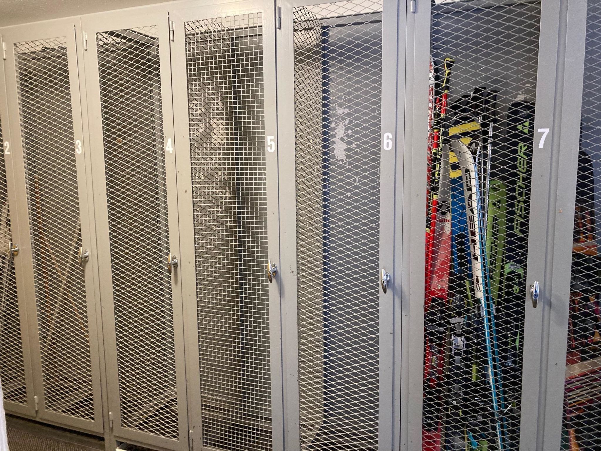 A row of six numbered metal lockers with mesh doors, likely used for storage.