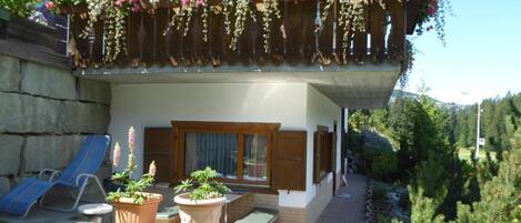 A two-story building with a balcony adorned with hanging flower baskets.