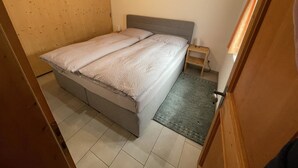 Un dormitorio con cama, mesita de noche y techo de madera.