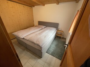 Ein Schlafzimmer mit einem Bett, einem Nachttisch und einer Holzbalkendecke.