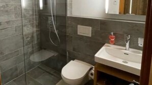 Un baño moderno con cabina de ducha de vidrio, inodoro y lavabo con espejo.
