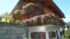 Una cabaña de madera de dos pisos con balcones decorados con cestas de flores colgantes.