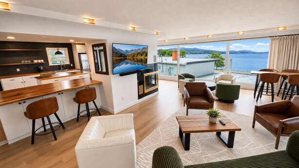 Una sala de estar moderna con cocina, comedor y balcón con vista al mar.