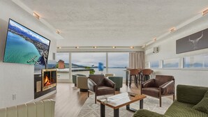 Amplia sala de estar con chimenea, sofás de cuero, una mesa de centro y un televisor grande.