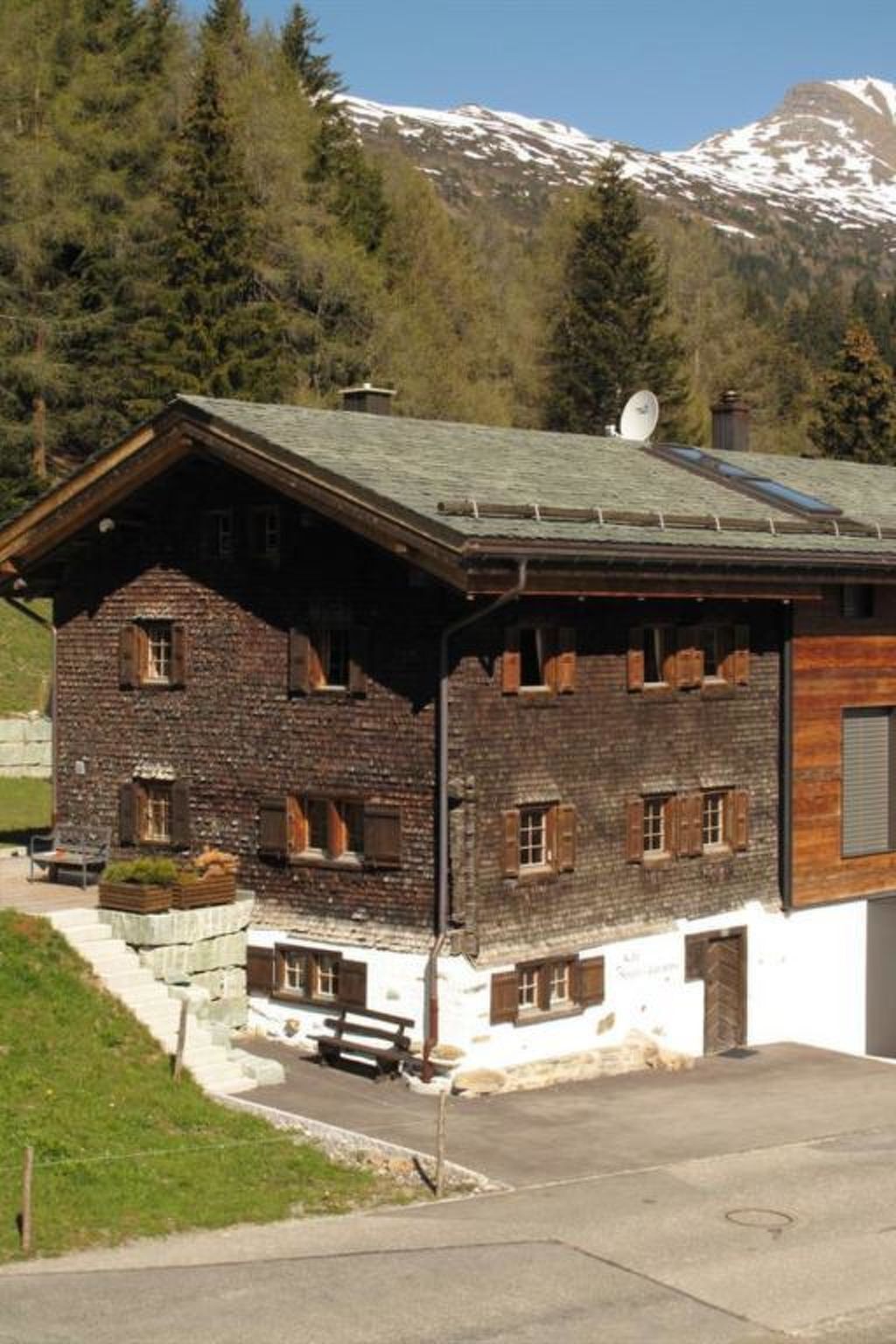Un chalet rustique avec une façade en pierre, des volets en bois et un toit en pente.