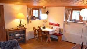 A cozy room with a wooden dining table, chairs, a sofa, and a lamp. - Acla Sporz Davains Appartement/Fewo, Dusche, WC, Wohn-/Schlafraum by Interhome (Lenzerheide)