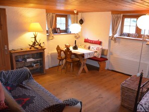 A cozy room with a wooden dining table, chairs, a sofa, and a lamp. - Acla Sporz Davains Appartement/Fewo, Dusche, WC, Wohn-/Schlafraum by Interhome (Lenzerheide)