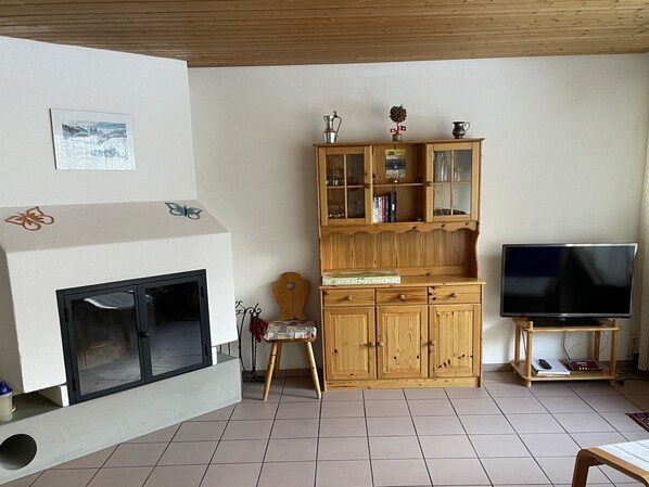 Una sala de estar con chimenea, un aparador de madera, televisor y una silla.