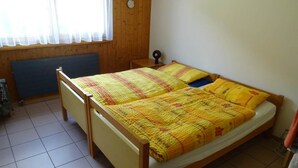 A single-bed room with a wooden frame, a window with sheer curtains, and a radiator below the window. - Soleval Tavanera 118 Moritz Appartement/Fewo,   5-Bettwohnung (3 Zimmerwohnung) by Interhome (Lenzerheide)