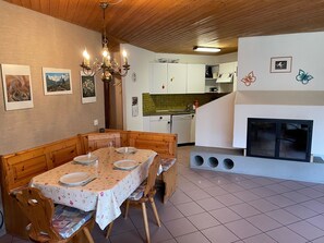 Ein Essbereich mit einem Holztisch, gedeckt für vier Personen, einer Kristallleuchtre und einer Küche im Hintergrund.