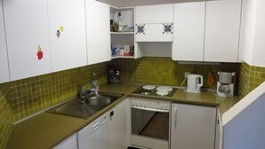 A compact kitchen with white cabinets, a green countertop, a sink, a stove, and a coffee maker. - Soleval Tavanera 118 Moritz Appartement/Fewo,   5-Bettwohnung (3 Zimmerwohnung) by Interhome (Lenzerheide)