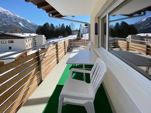 A balcony with a table and chairs, a view of snow-covered mountains, and a building in the background. - Haus Montana 1/9 Appartement/Fewo,   5-Bettwohnung by Interhome (Lenzerheide)