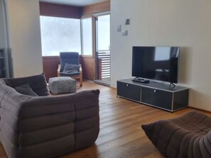 A living room with a sofa, ottoman, and a TV on a cabinet. - Clavo Vigl Appartement/Fewo Clavo Vigl by Interhome (Vaz)