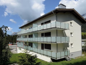 A multi-story building with balconies, a staircase, and a view of mountains. - Haus Montana 3/3 Appartement/Fewo,   4-Bettwohnung by Interhome (Lenzerheide)
