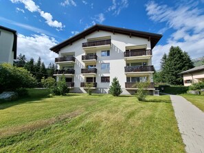 A multi-story residential building with balconies, a paved walkway, and surrounding greenery. - Ferienwohnung Degen Appartement/Fewo,   Ferienwohnung Degen by Interhome (Valbella)