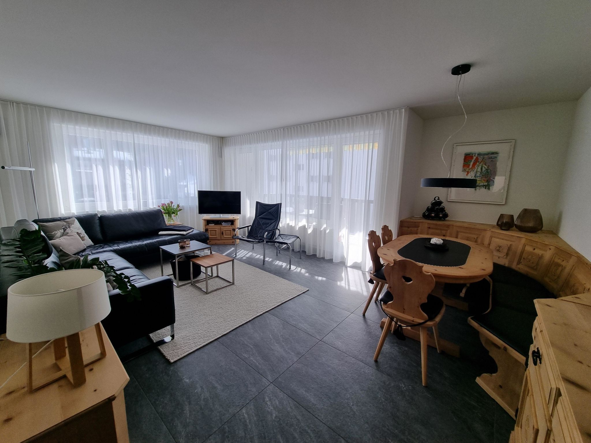 Un salon moderne comprenant un canapé, un téléviseur, une table basse et un coin repas avec des chaises et une table.