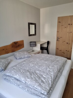 Une chambre à coucher comprenant un lit, une table de chevet, une lampe, une chaise et une armoire.