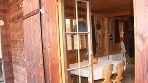 Ein Interieur einer Holzhütte mit Esstisch, Stühlen und einer Küchenzeile.