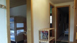 Ein Zimmer mit Etagenbetten, einer Holzregaleinheit und einem gefliesten Boden.