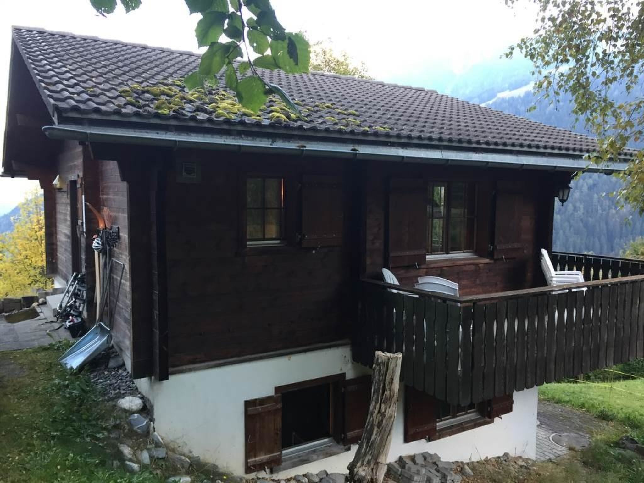 A wooden chalet with a balcony, a ski lift, and a mountain view.