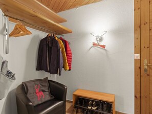 A room with a coat rack, a chair, a shoe rack, and a wall-mounted light fixture. - Schweizerhof 424 Walker Appartement/Fewo,   2.5 Zimmerwohnung by Interhome (Lenzerheide)