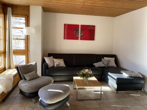 A modern living room with a sectional sofa, a coffee table, and a large window providing natural light. - Schweizerhof 424 Walker Appartement/Fewo,   2.5 Zimmerwohnung by Interhome (Lenzerheide)