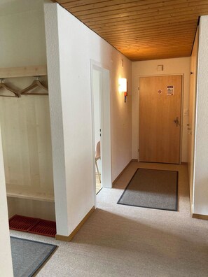 A hallway with a wooden door, a light fixture, and a mat at the entrance. - Haus Montana 1/6 Appartement/Fewo,   5-Bettwohnung by Interhome (Lenzerheide)