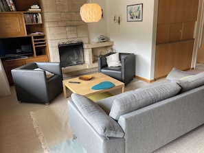 Ein Wohnzimmer mit Kamin, einer Couch, einem Couchtisch und einem Bücherregal.