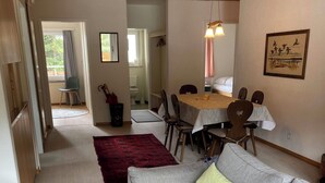Una sala de estar con un sofá gris, un tapete rojo y un comedor con mesa y sillas.