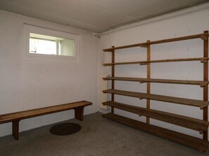 Ein Zimmer mit weißer Wand, einer Holzbank, einem Fenster und einer Holzkassette.
