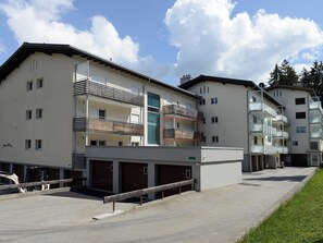 A multi-story residential building with balconies, a garage area, and a clear sky. - Haus Montana 1/6 Appartement/Fewo,   5-Bettwohnung by Interhome (Lenzerheide)