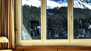 A bed with a view of a snowy mountain landscape through a window. - Haus Curver Bächtold Appartement/Fewo,   5-Bettwohnung (4.5 Zimmerwohnung) by Interhome (Valbella)