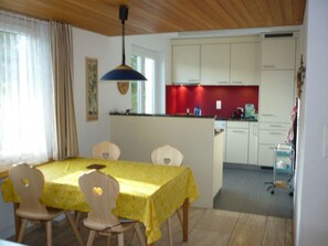 Ein Essbereich mit Tisch und Stühlen, eine Küche mit Schränken und ein Deckenventilator.