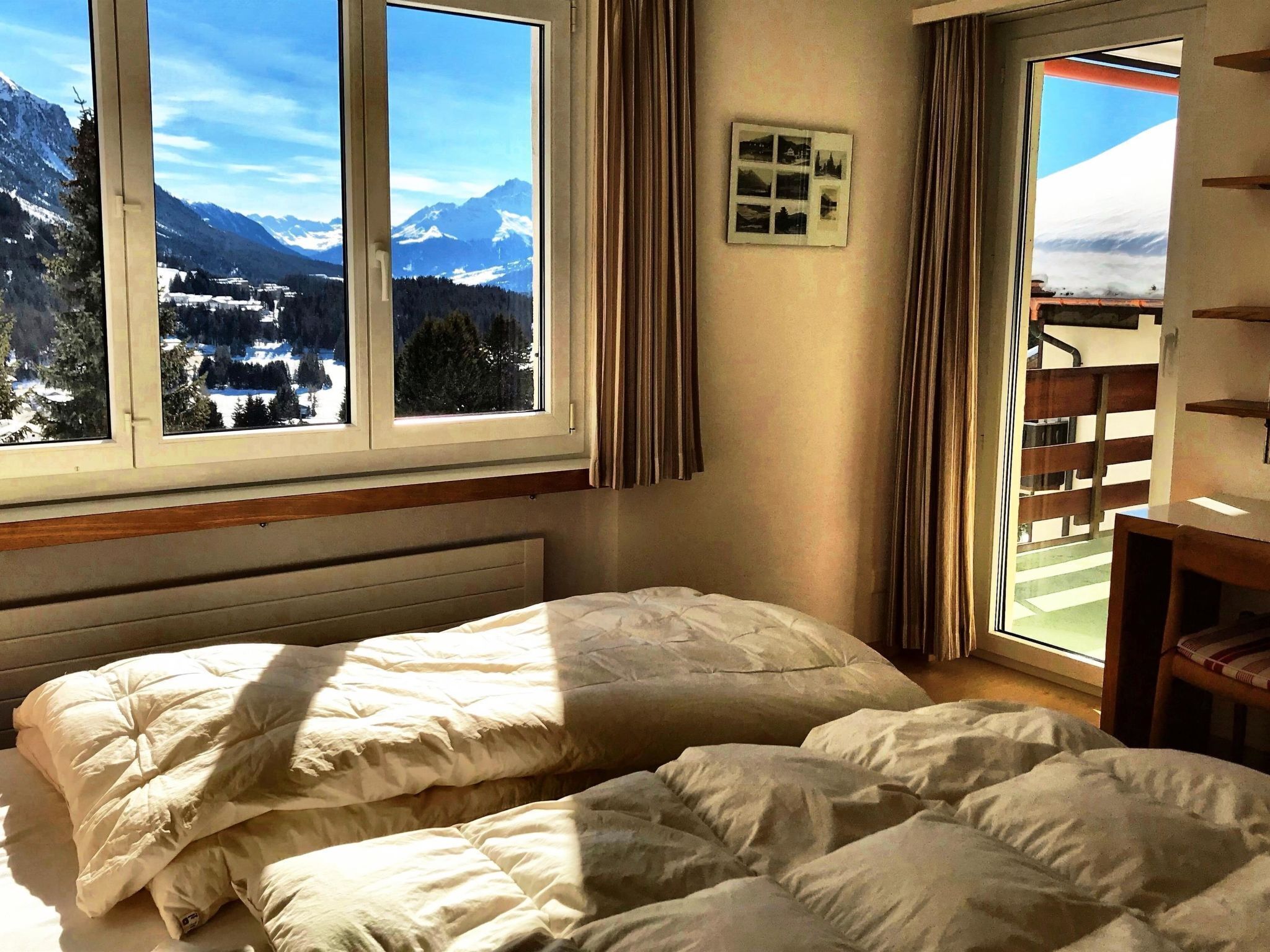 A bedroom with a bed, a window with a mountain view, and a curtain.