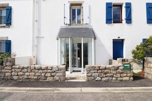 A white building with blue shutters, a stone wall entrance, and a number '2' sign. - Pen Er Bed - GAVRES - Gîte (GAVRES)